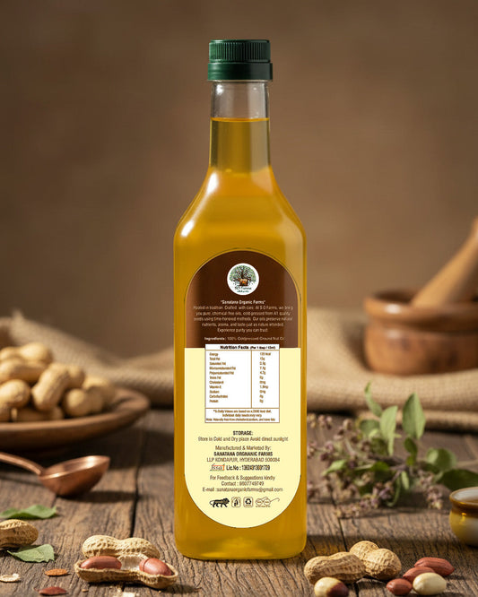 Bottle of peanut oil with a label on a rustic wooden table with peanuts and a mortar and pestle.