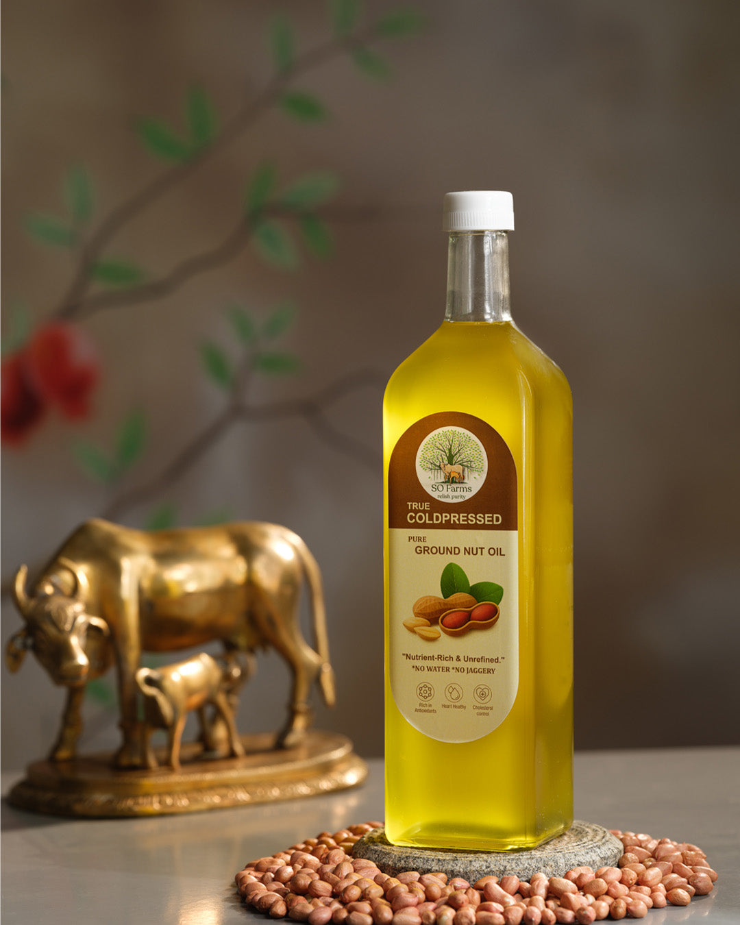 Bottle of groundnut oil with a label on a surface, featuring scattered peanuts.